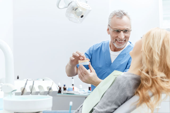 a denturist showing suction dentures to a patient