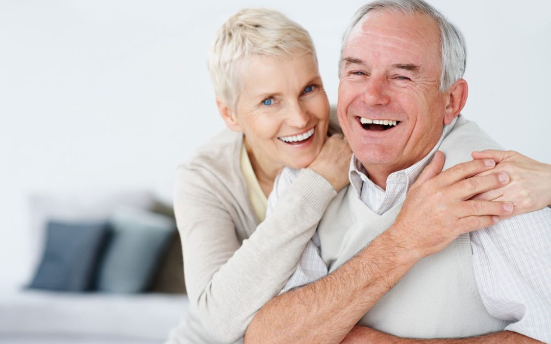 an elderly couple smiling with their dentures