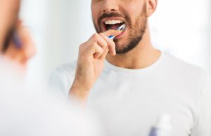 a man brushing his teeth in front of the mirror