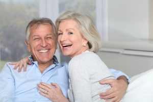 an elderly couple smiling happily after getting dentures